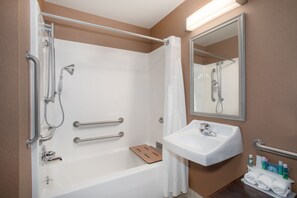 A modern bathroom with a bathtub, shower, and sink. It includes grab bars, a mirror, and a towel rack. - Holiday Inn Express & Suites Yankton by IHG (Yankton)