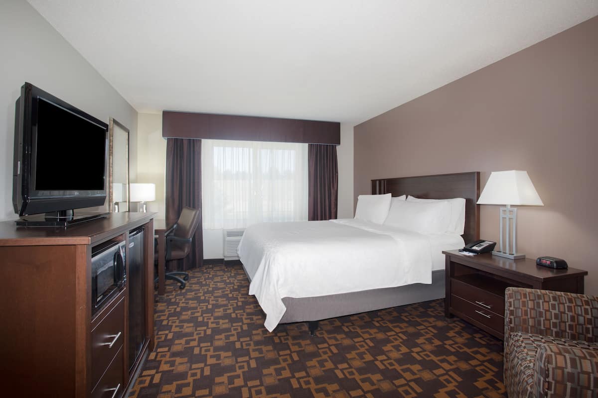 A hotel room with a bed, a television, a desk, and a chair.