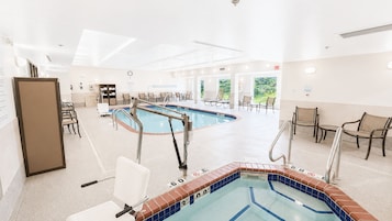 Zona de piscina hotelera con jacuzzi, sillones de descanso y un espacio de estar con vistas al exterior.
