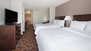 A hotel room with two beds, a TV, a desk, and a patterned carpet.