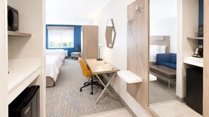 Una habitación de hotel con cama, escritorio, silla y sofá.