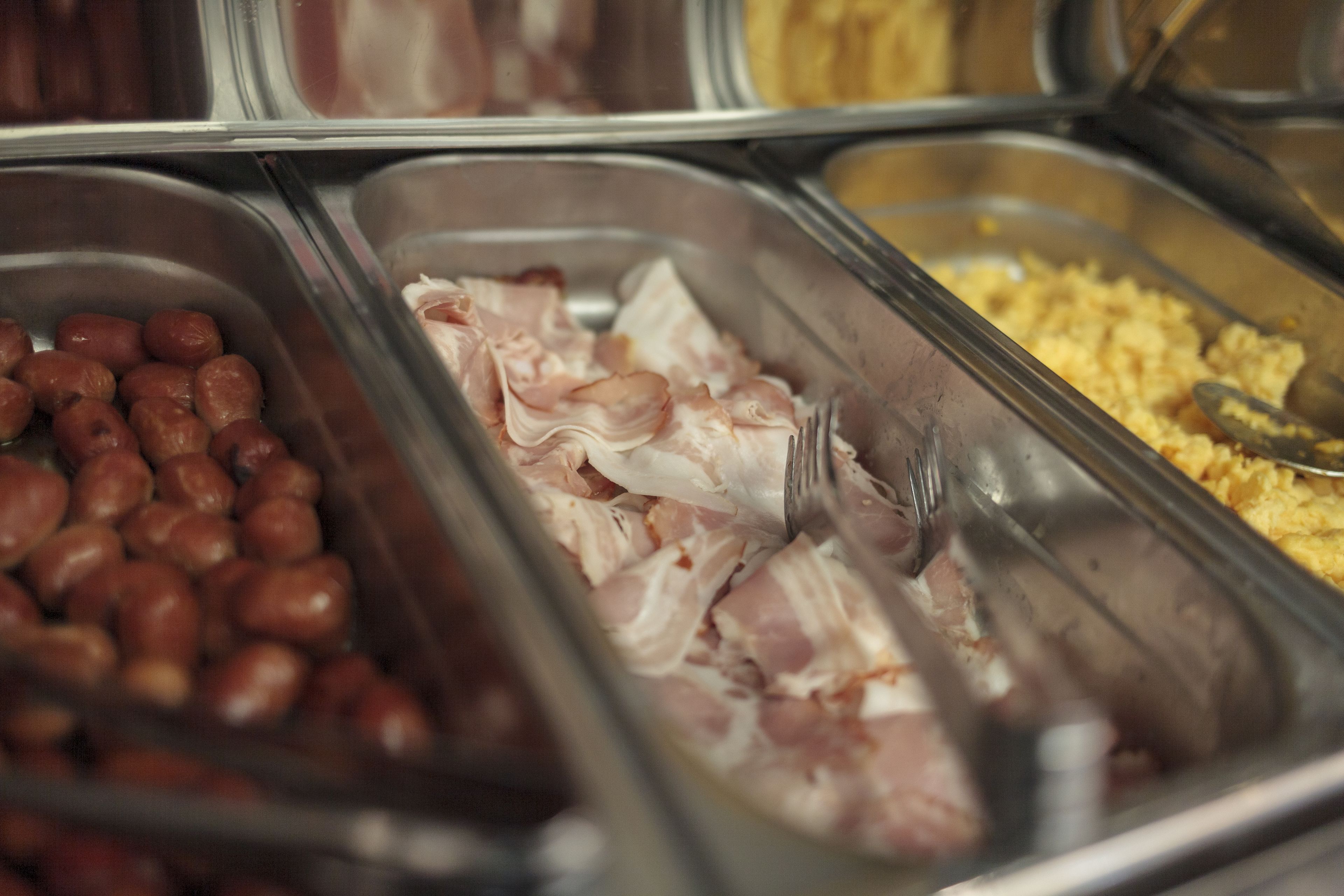 A buffet with various food items including beans, bacon, and scrambled eggs.