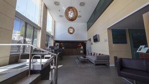 A modern lobby with a staircase, seating area, and a reception desk. - Hotel Salymar (San Fernando)