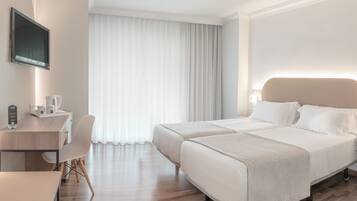 Una habitación de hotel con cama, mesita de noche, lámpara y escritorio con silla.