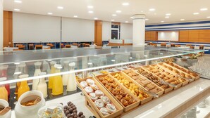 Un área de bufé con diferentes opciones de comida y una vitrina de vidrio.