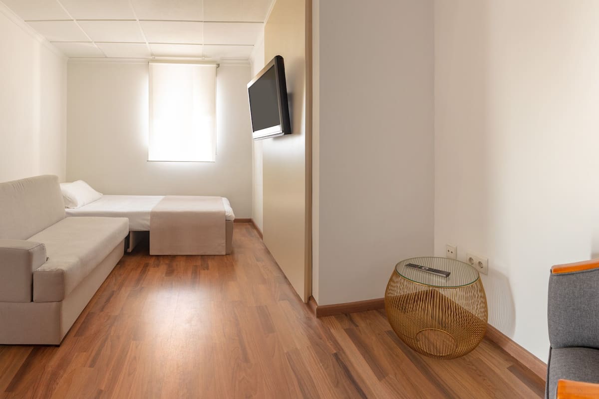 A modern, well-lit room with a sofa, a small table, and a television mounted on the wall.