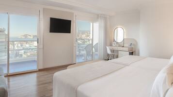 Une chambre d’hôtel avec un balcon, un lit, un bureau, une chaise et une télévision.