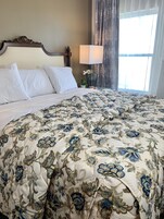 Una cama bien hecha con sábanas blancas y una colcha de diseño floral.