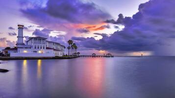 A waterfront property with a lighthouse, a white building, and a pier extending into the water.