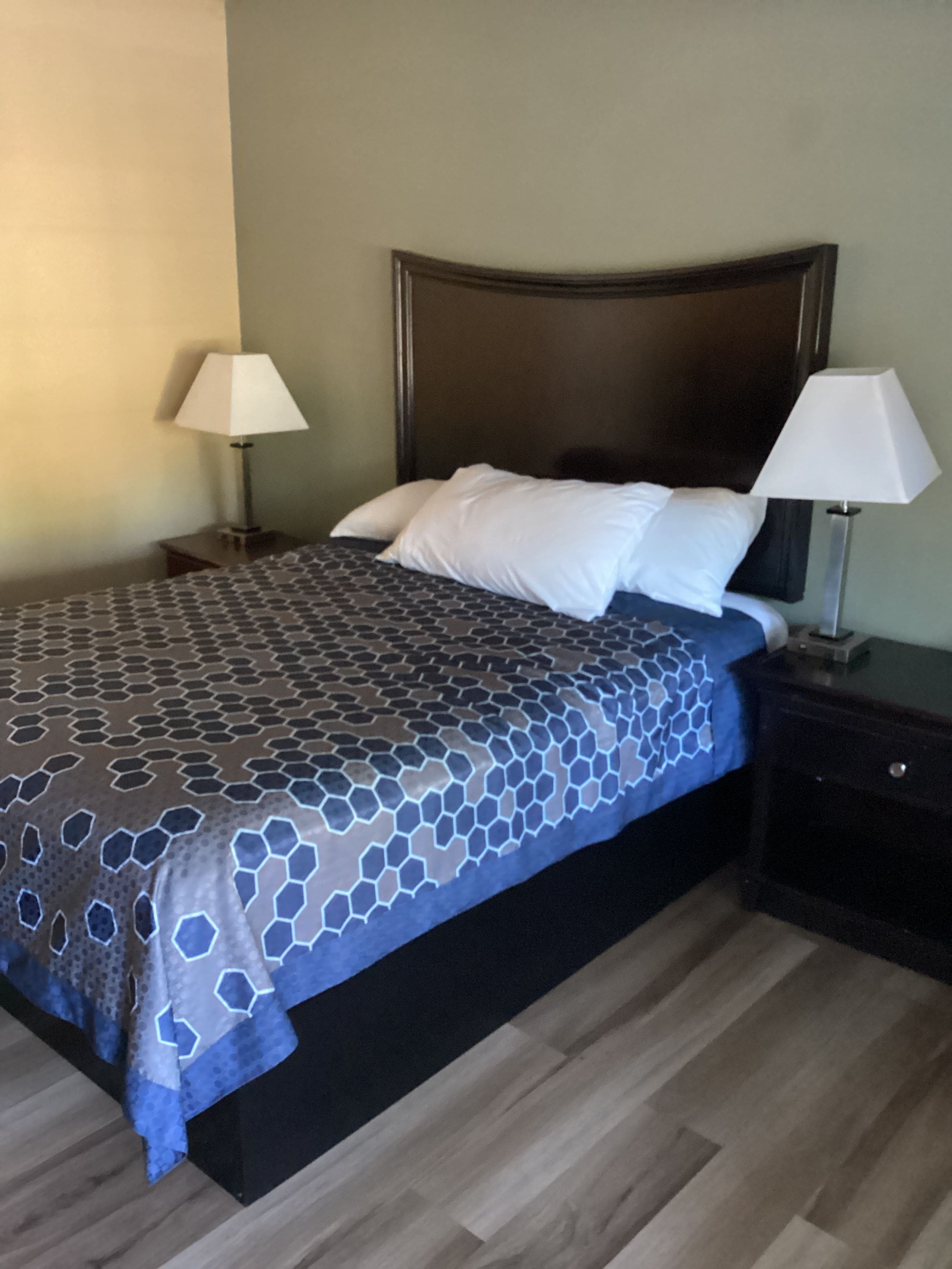 A bed with a patterned bedspread, two bedside lamps, and a dark headboard.