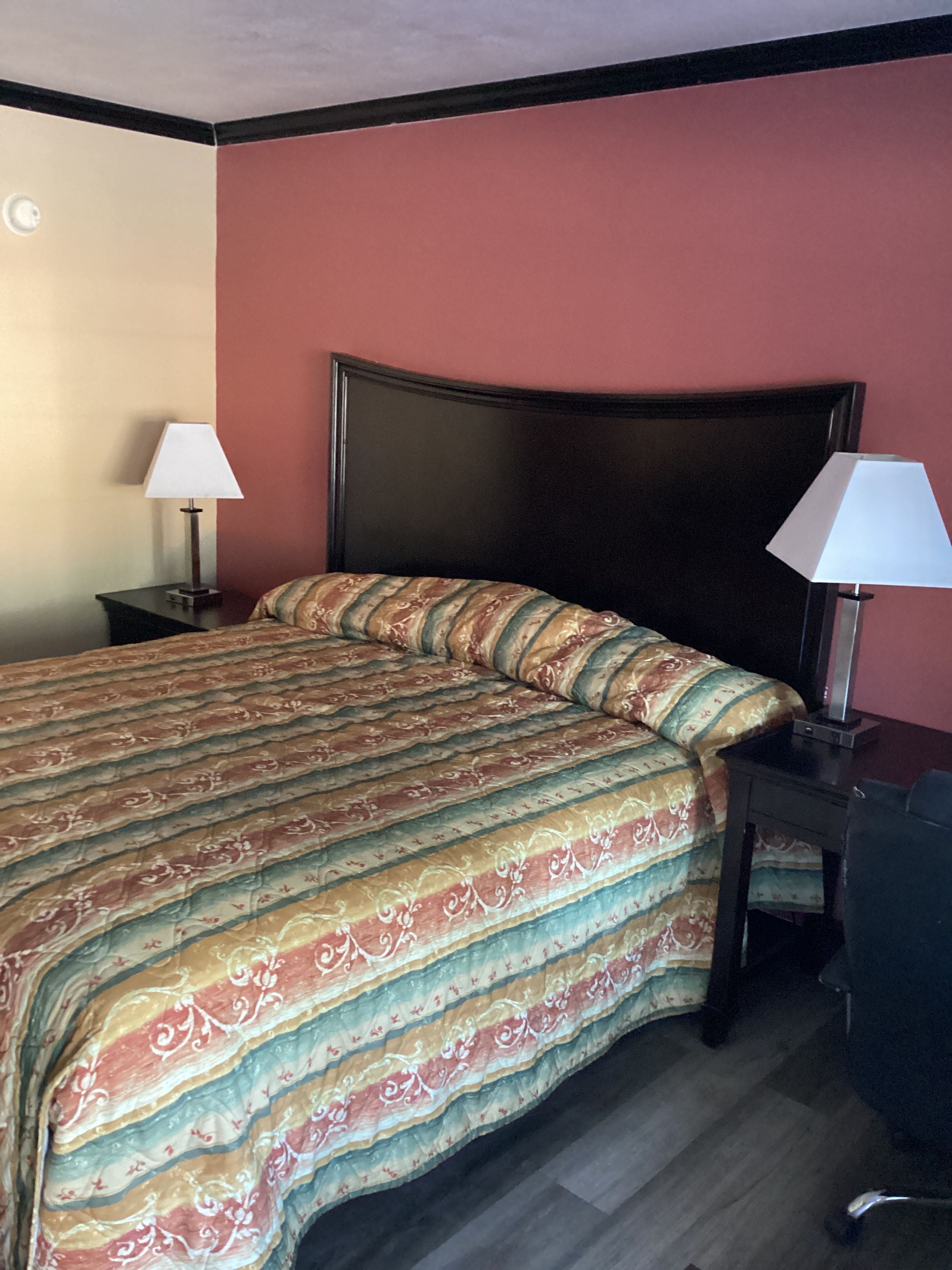A hotel room with a bed, two bedside tables, and a desk.