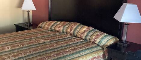 A hotel room with a bed, two bedside tables, and a desk.