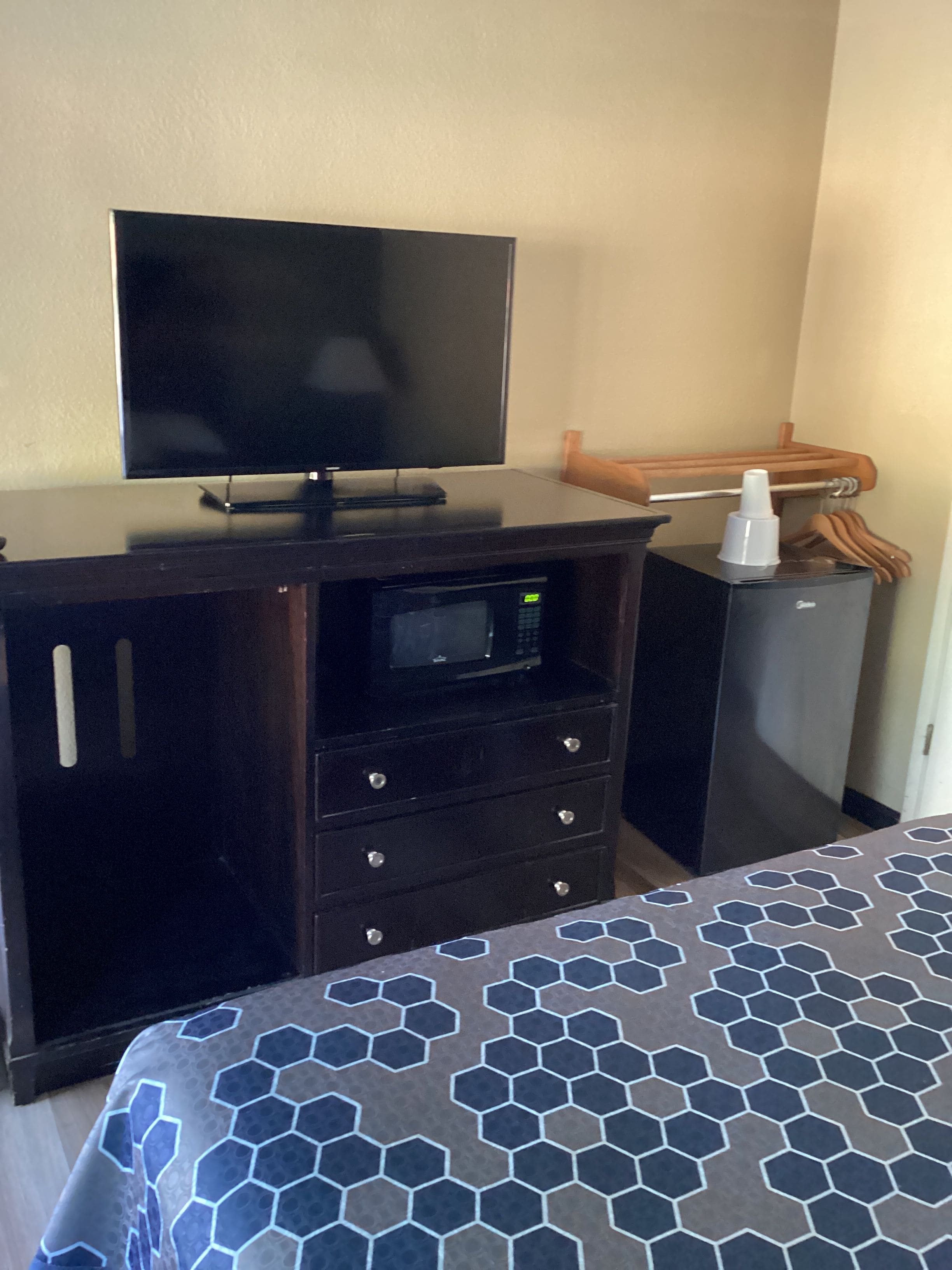 Habitación de hotel con cama, televisor de pantalla plana, minibar y una silla de madera.