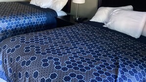 A hotel room with two beds, a nightstand with a lamp, and a plain wall. - Town House Motel Chico (Chico)