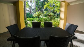 A dining area with a table and chairs, surrounded by a view of tropical greenery. - Lemon Tree Inn (Santa Barbara)
