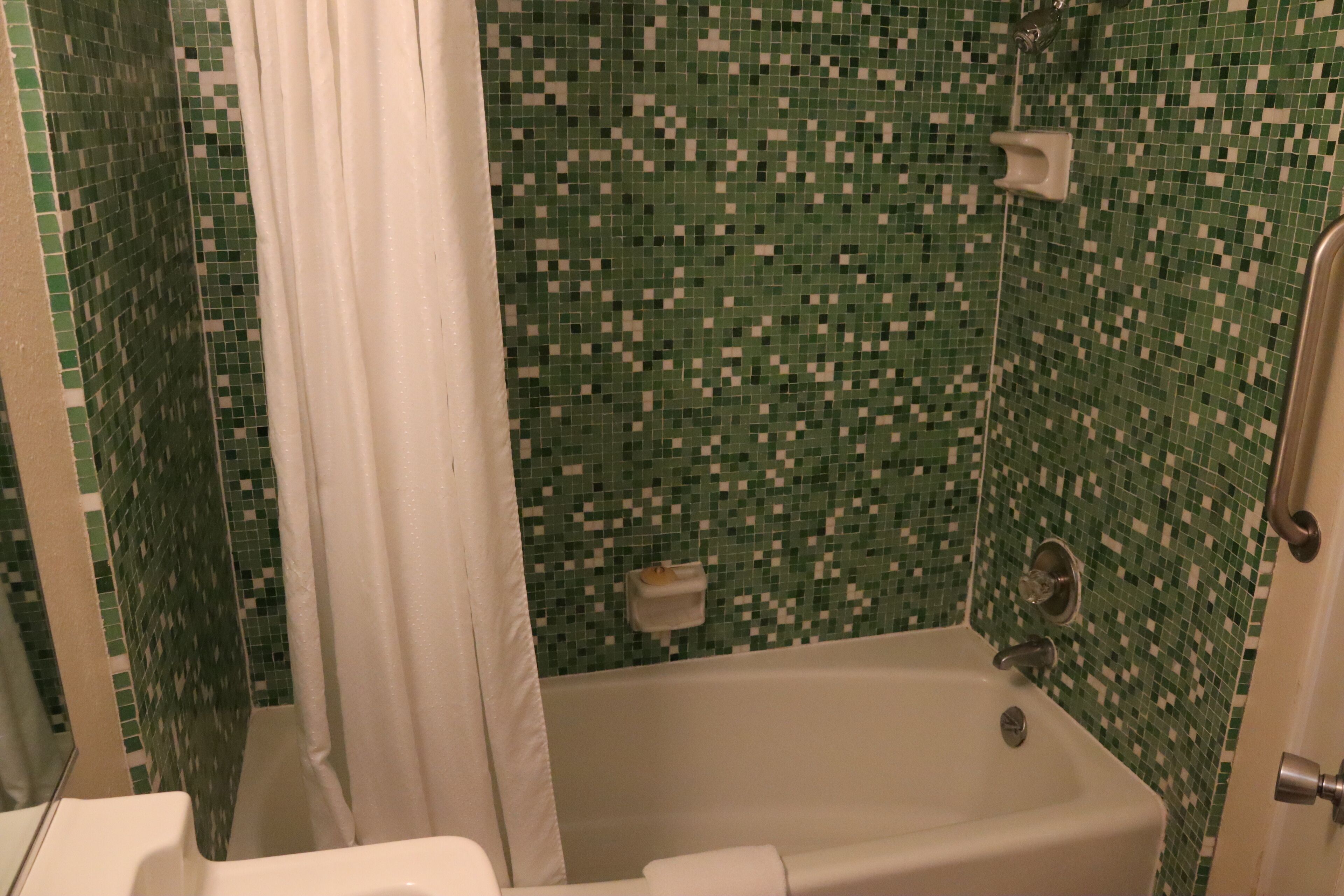 A bathroom with a bathtub, a shower, and a tiled wall.