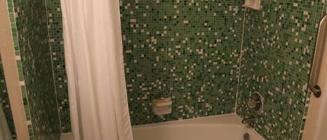 A bathroom with a bathtub, a shower, and a tiled wall.