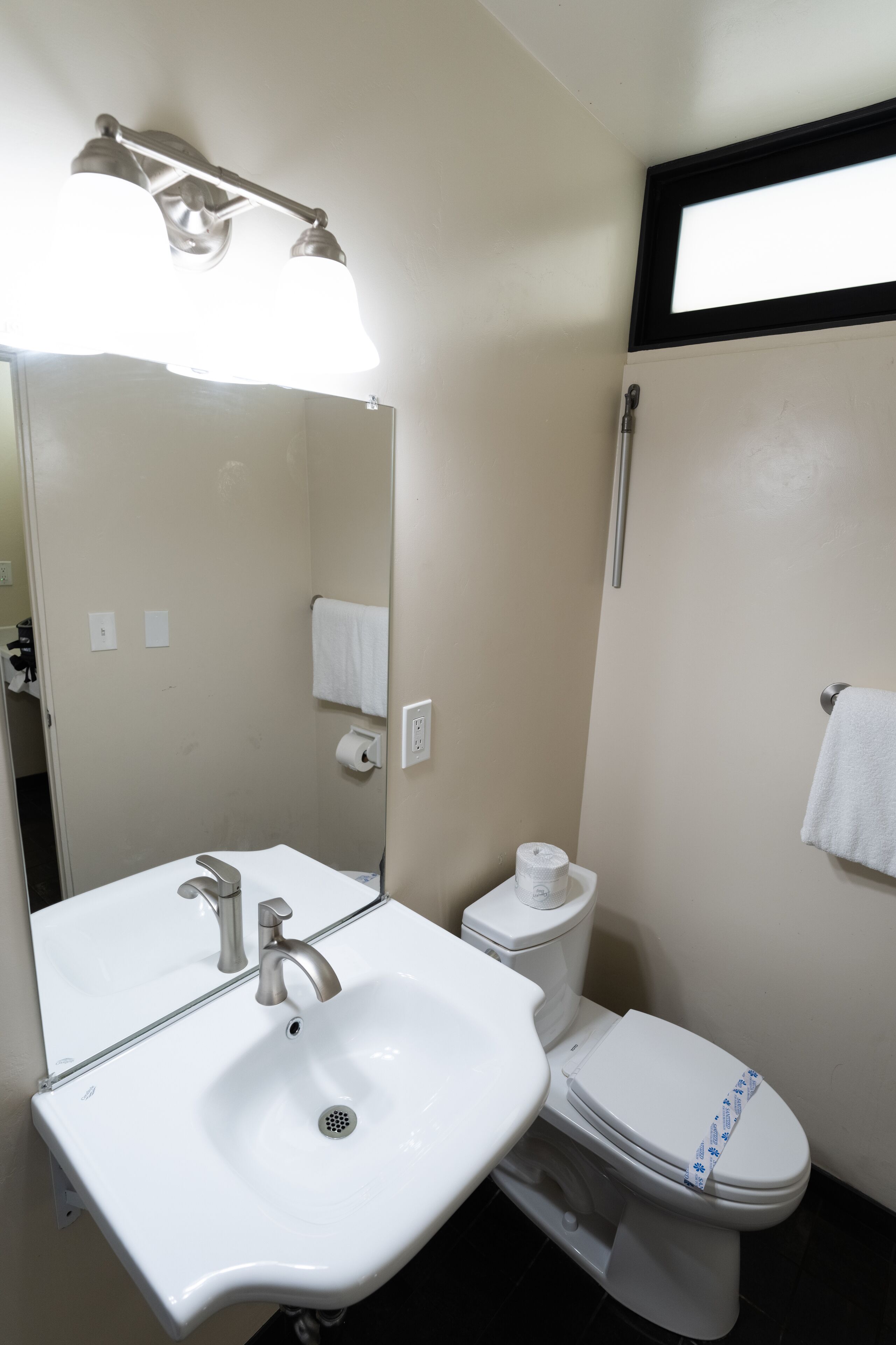 A bathroom with a white sink, mirror, and toilet.