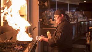 A chef cooking with a large flame in a kitchen. - Lemon Tree Inn (Santa Barbara)