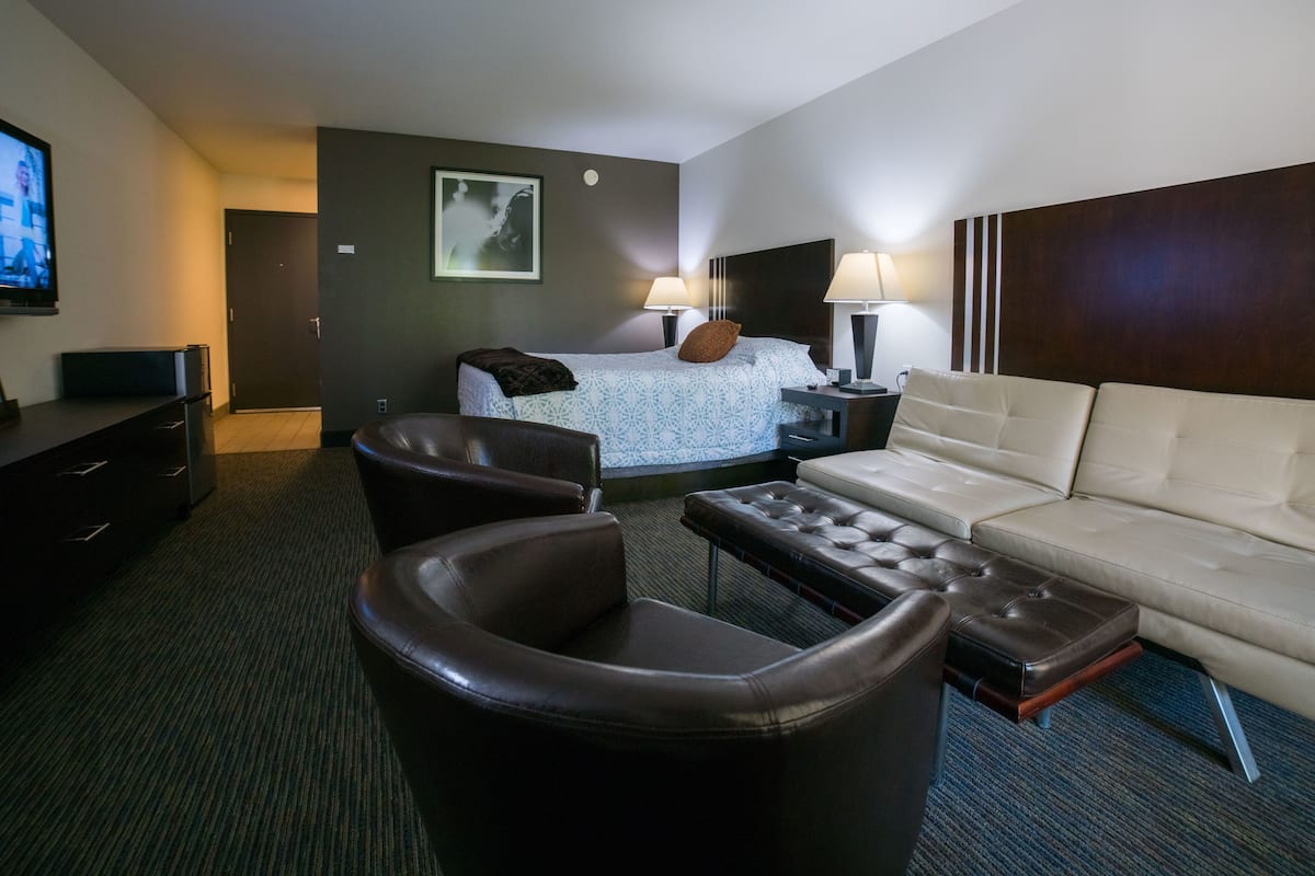 A hotel room with a bed, a sofa, a chair, a TV, and a desk.