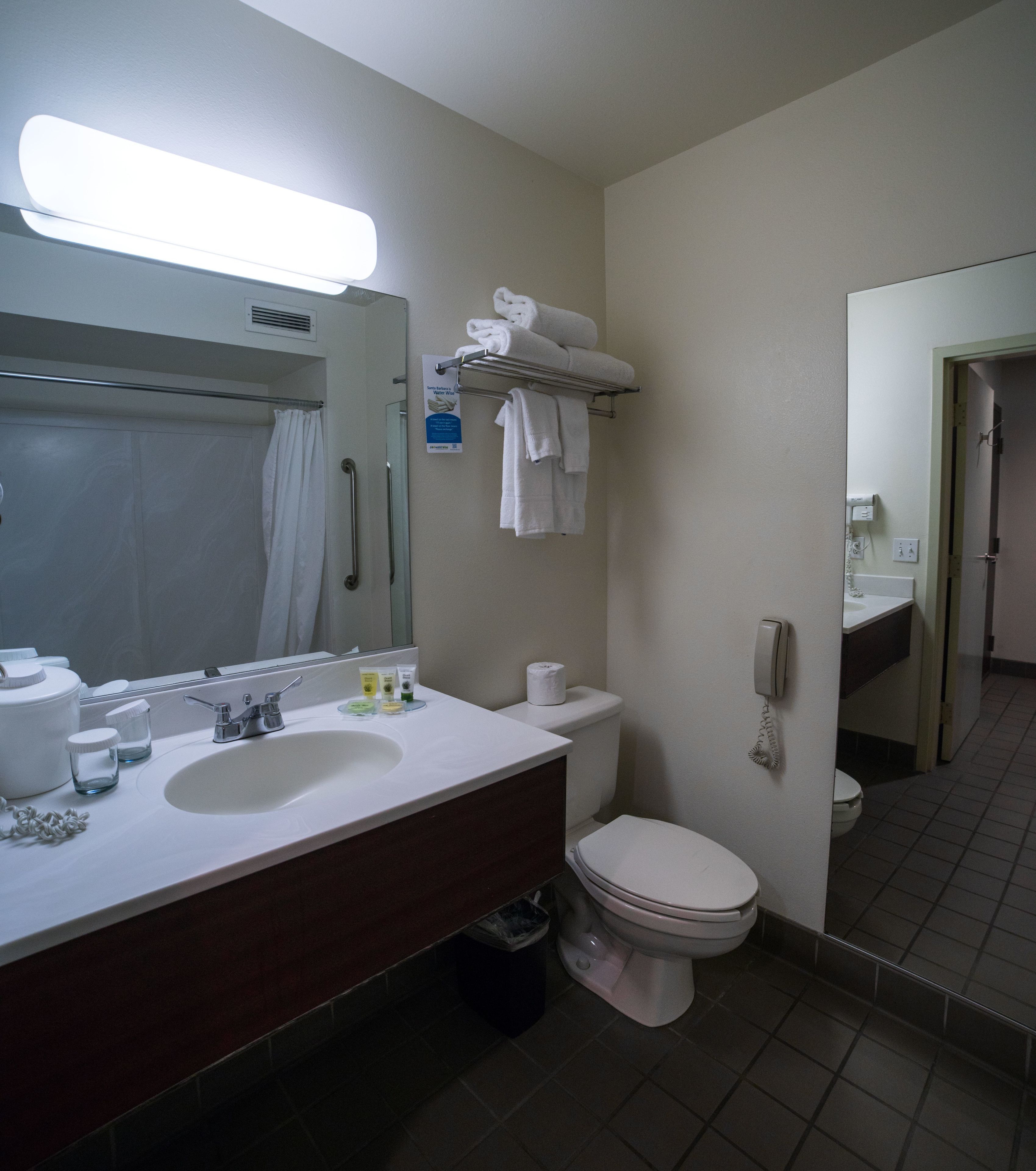 Een badkamer met een wastafel, spiegel, toilet en handdoekhouder.