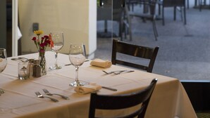 A dining area with a table set for two, a vase with flowers, and a view of the outdoor seating area. - Lemon Tree Inn (Santa Barbara)