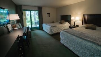 Habitació d'hotel amb dos llits, un escriptori, una cadira, una televisió i una finestra amb cortines.