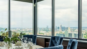 A dining table set for two with a city view through large windows.