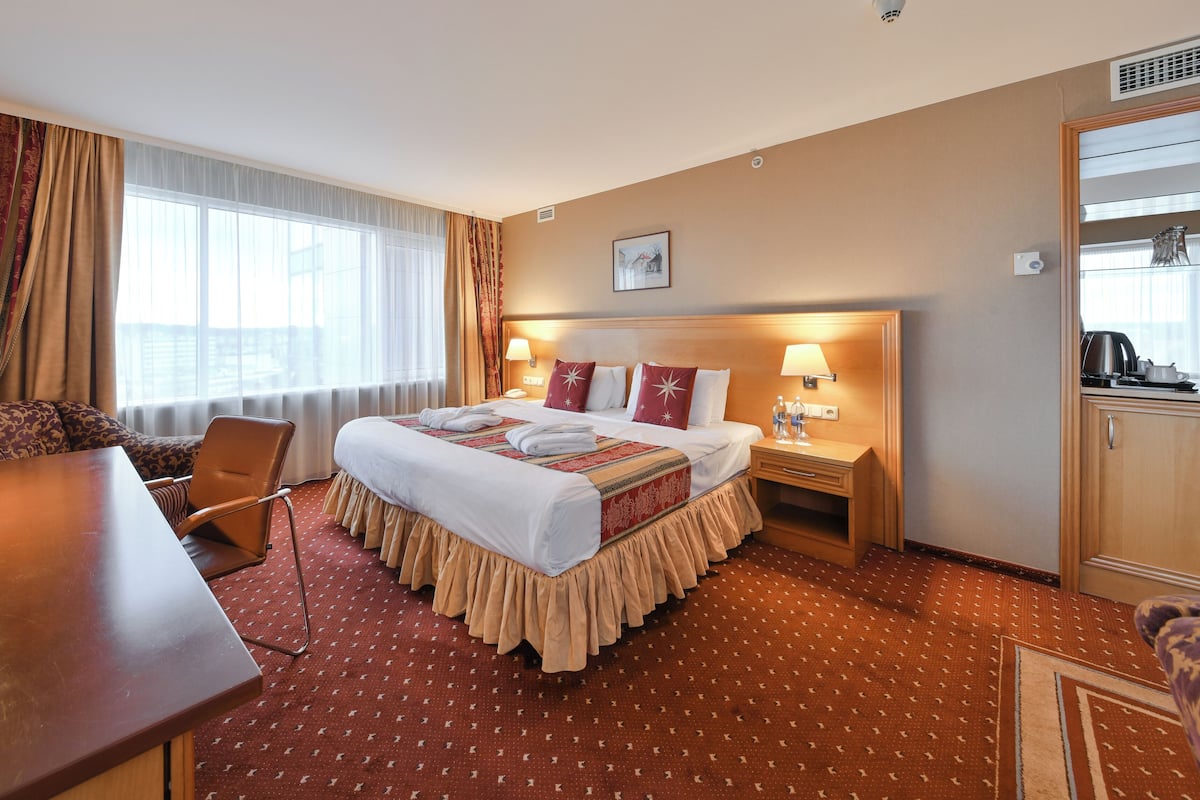 Une chambre d’hôtel comprenant un lit, un bureau, une chaise, une table de chevet et une kitchenette.