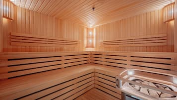 Un sauna avec des bancs en bois et un grand bain à remous au centre.