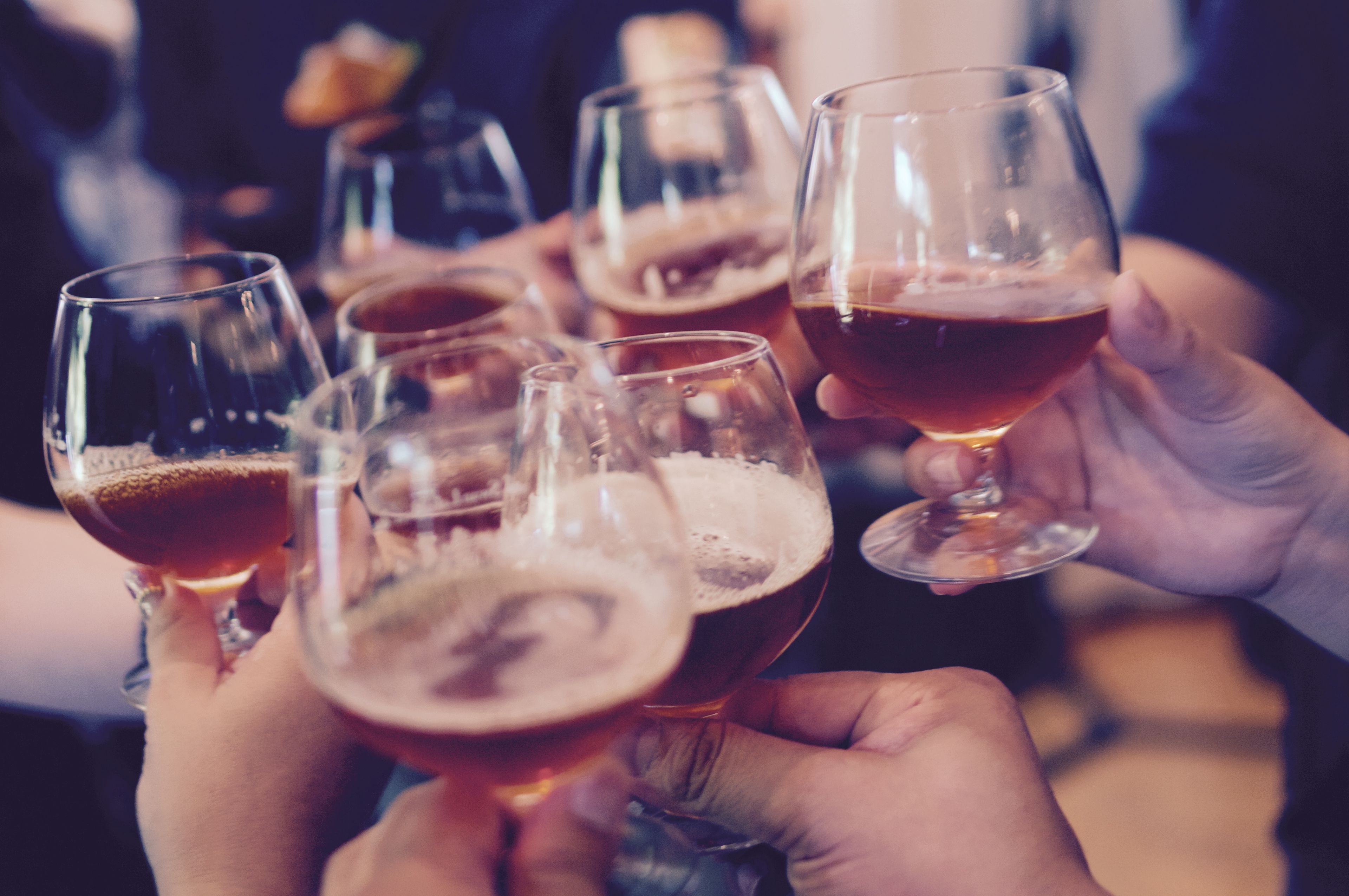 Un grupo de personas levantando copas de cerveza, probablemente en una reunión social o evento.