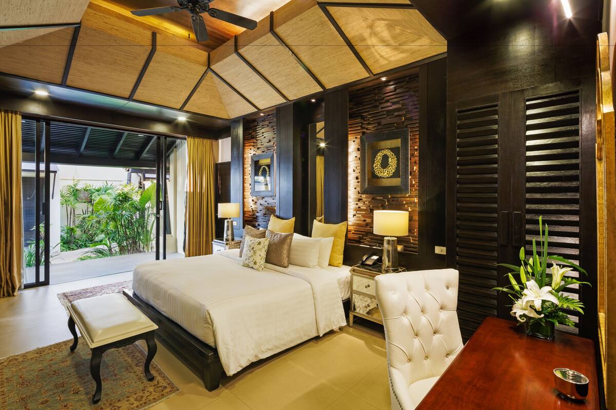 Um quarto espaçoso com uma cama grande, um espaço de estar e vista para o verde.