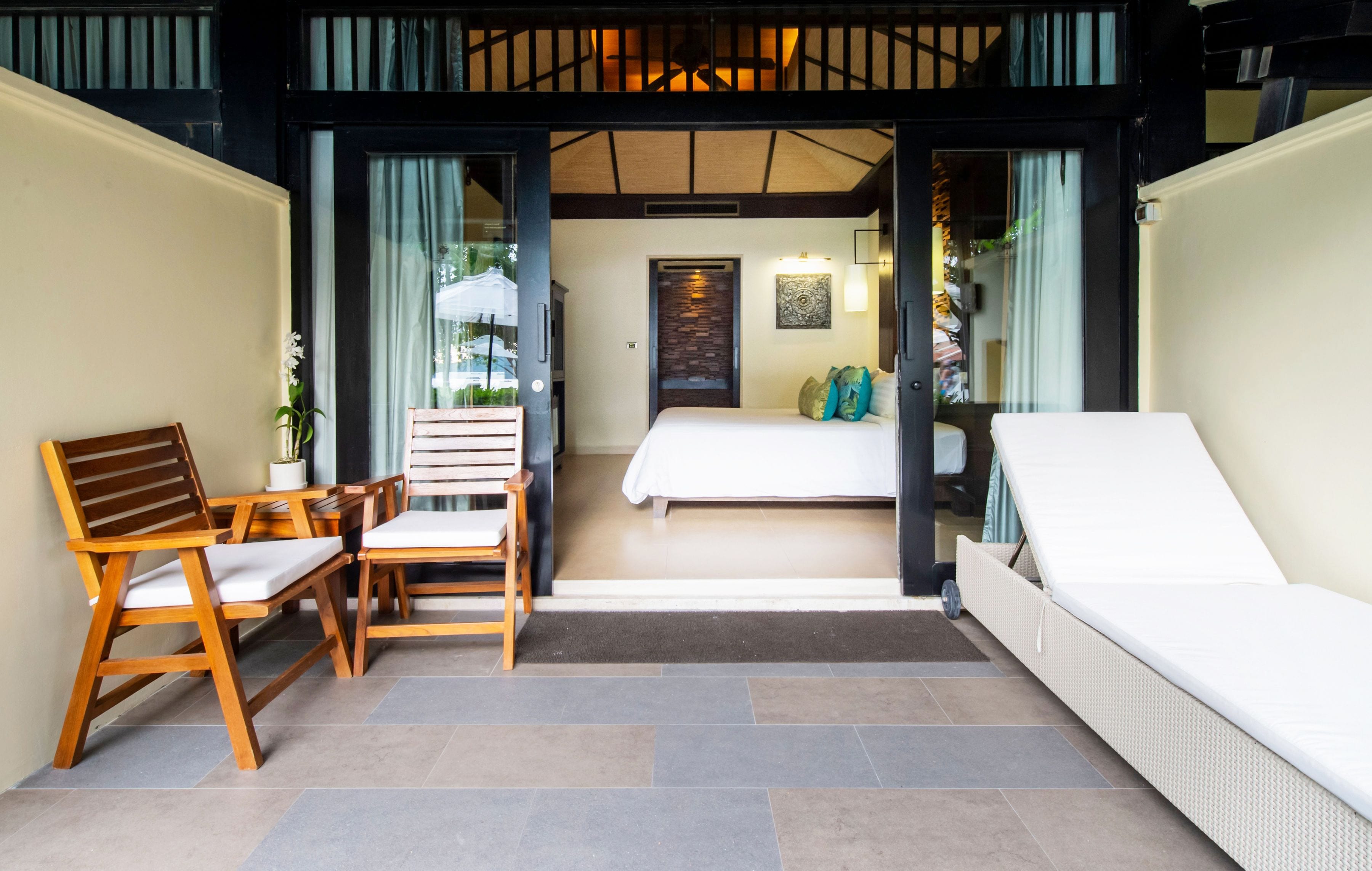 A room with a bed, a sitting area with chairs, and a small table.