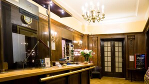 A reception area with a wooden counter, a clock, a Coca-Cola refrigerator, and a chandelier. - Hotel Aster (Berlin)