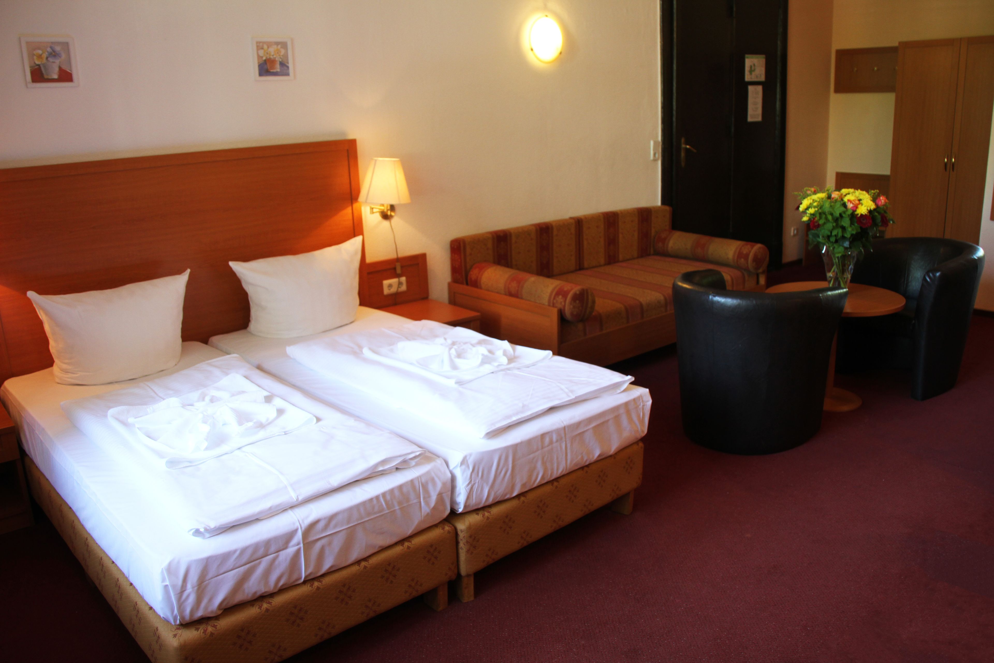 A hotel room with two beds, a sofa, a small table, and a lamp.