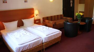 A hotel room with two beds, a sofa, a small table, and a lamp.