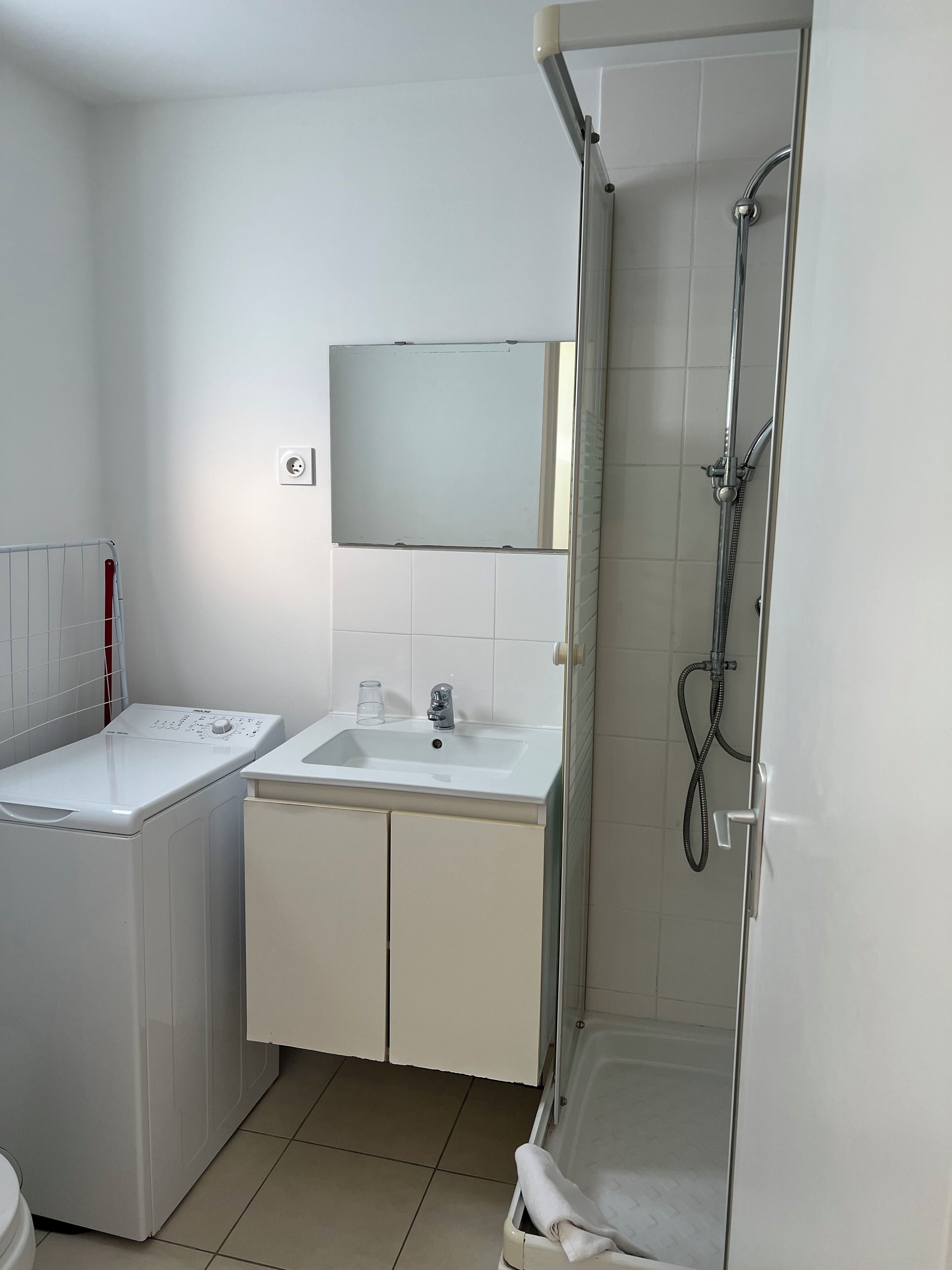 Un bagno con lavatrice, lavandino, specchio e doccia.