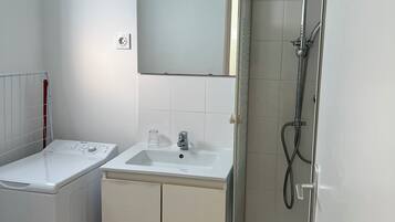 Un bagno con lavatrice, lavandino, specchio e doccia.