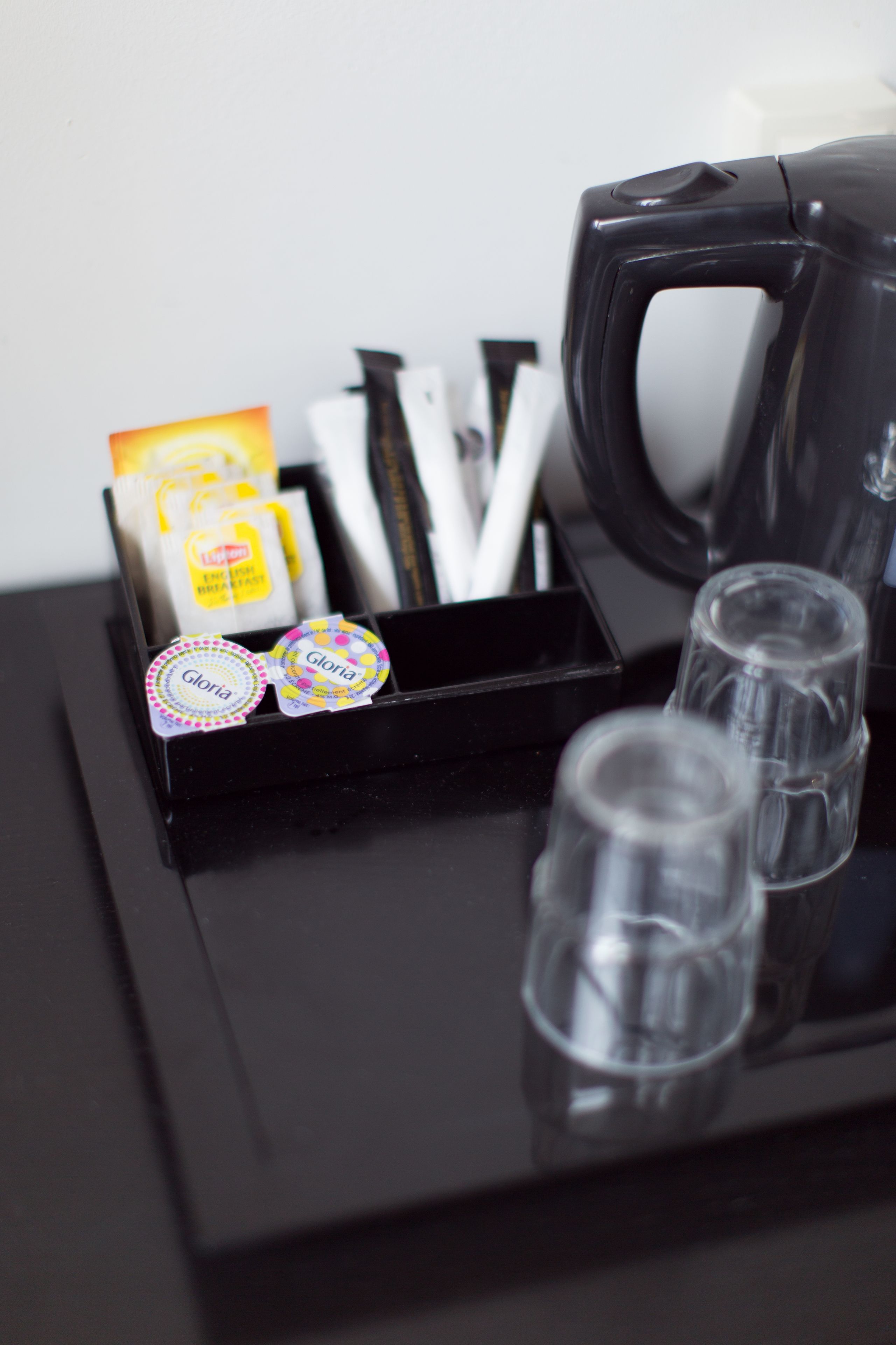 A tray with a coffee maker, a box of tissues, and a set of shot glasses.