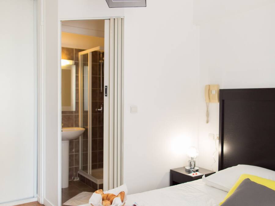 A hotel room with a bed, bedside table, and a tray with breakfast items.