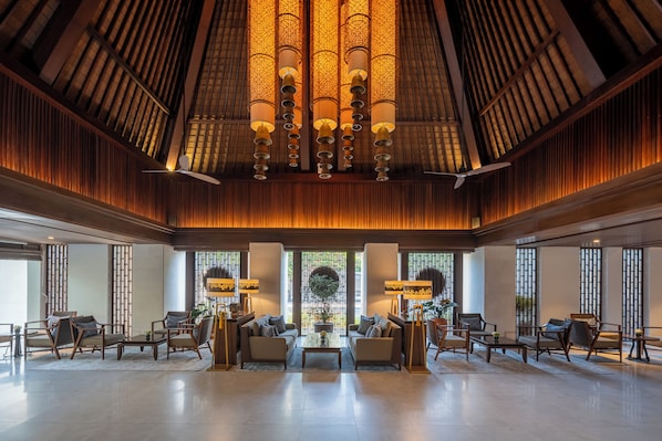 A spacious lobby with a high ceiling, traditional wooden paneling, and a central chandelier.