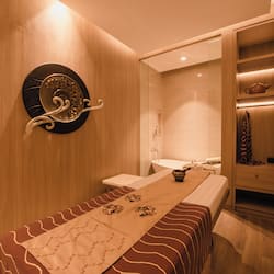 Relax in a serene space with a long, neatly made bed and a decorative plate on the wall.