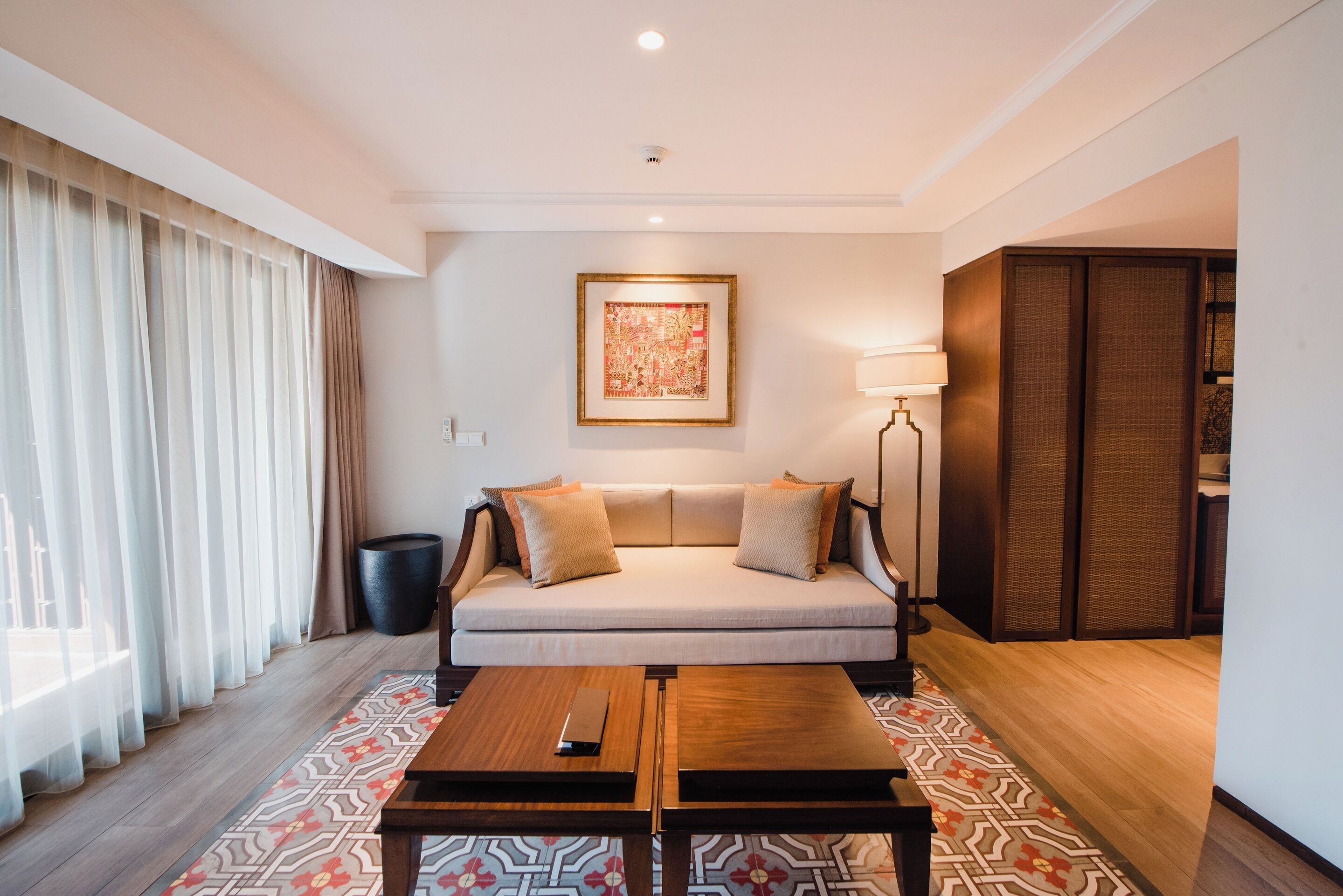 Une chambre d’hôtel moderne, dotée d’un canapé, d’une table basse, d’une œuvre d’art encadrée au mur et d’une porte coulissante de style japonais traditionnel.