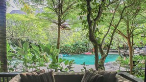 Un espacio de descanso junto a la piscina con un banco acolchado y un libro.