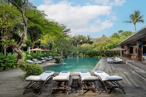 A poolside area with lounge chairs, a wooden deck, and lush greenery. - Ramayana Suites & Resort (Kuta)