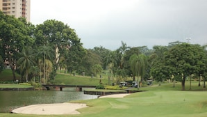 A golf course with a pond, palm trees, and a bridge. - A'Famosa Resort (Alor Gajah)