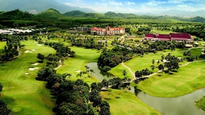 A golf course with a large building in the background. - A'Famosa Resort (Alor Gajah)