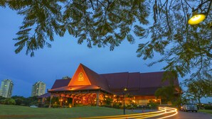 A hotel with a distinctive red roof and a large sign. It is situated on a paved area with a grassy foreground. - A'Famosa Resort (Alor Gajah)