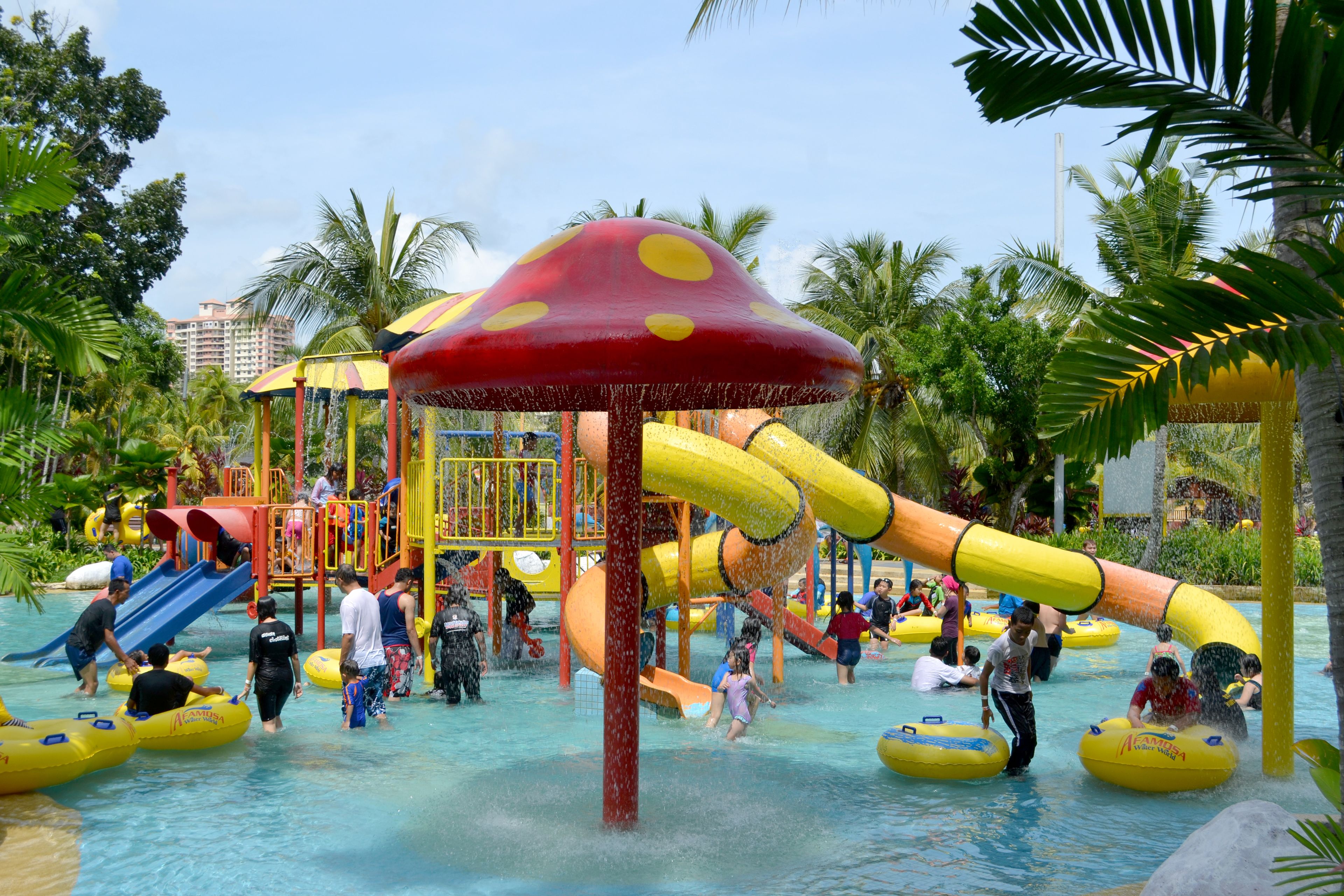 A water park with slides, inflatable rafts, and a large mushroom-themed play structure.