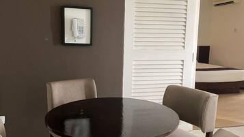 Un comedor con una mesa redonda y cuatro sillas, una lámpara colgante blanca y un cuadro con una foto de un teléfono en la pared.